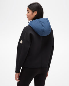 Aspen Collection Aether Align Hooded Anorak, view from back. Black base of hoodie with athletic material, blue puffey hood