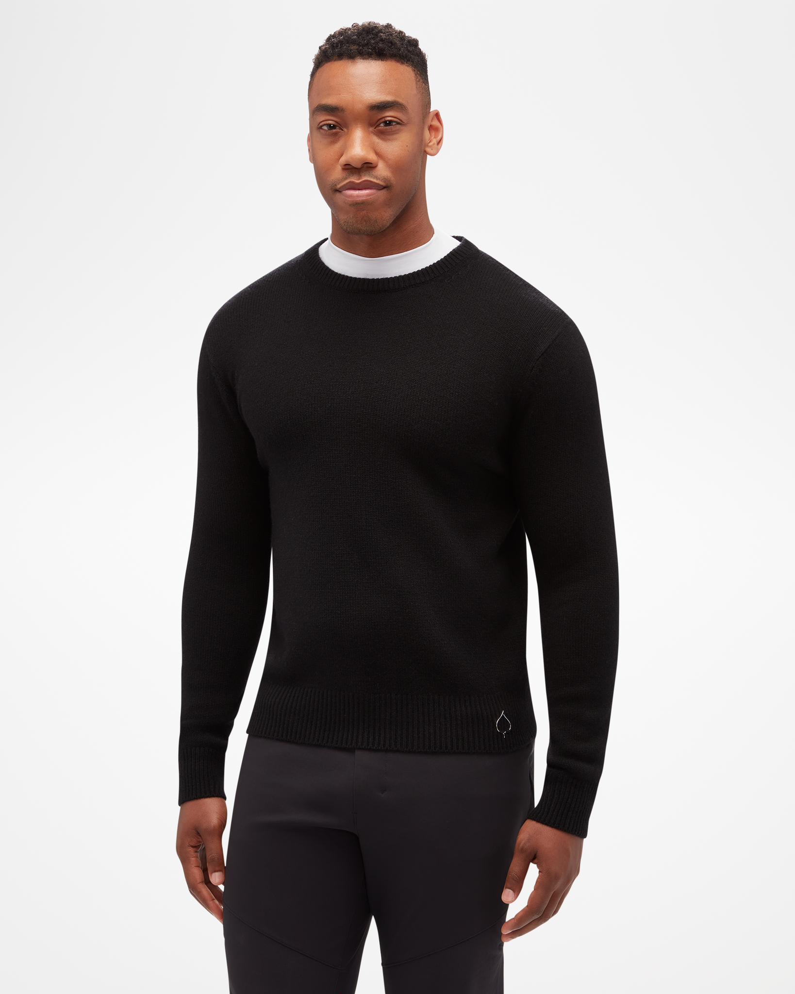 Aspen Collection men's Cashmere Crewneck, simple fitted knit, in black. Front view of model, with small aspen leaf logo on bottom.