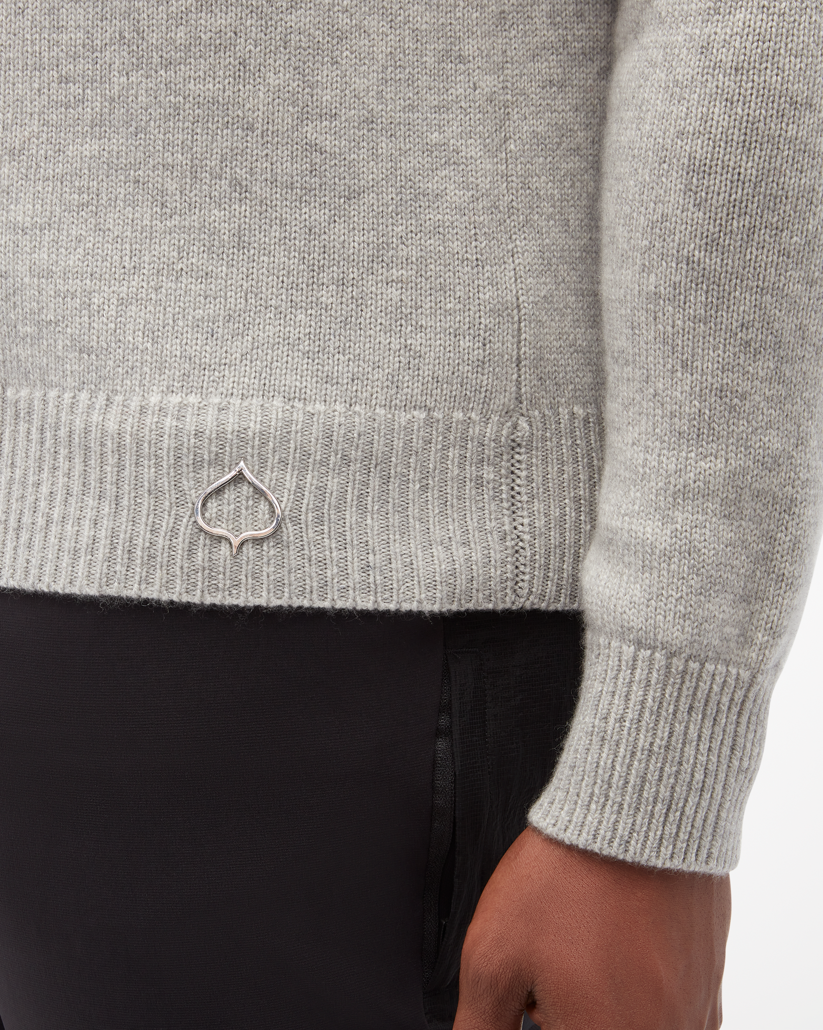 Aspen Collection men's Cashmere Crewneck, in grey color. focused view of cuff on wrist and small logo on bottom of sweater.